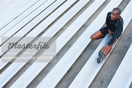 Man stretching on bleacher, high angle view