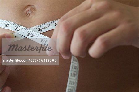 Woman measuring stomach, cropped