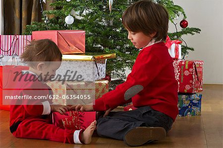 Young brother and sister opening Christmas gift together