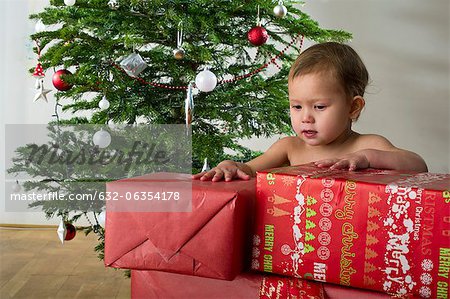 Baby girl touching stacked Christmas presents