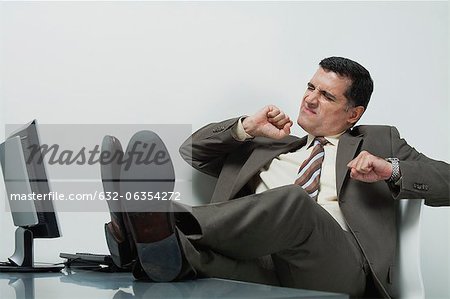 Businessman sitting in office with feet up on desk - Stock Photo