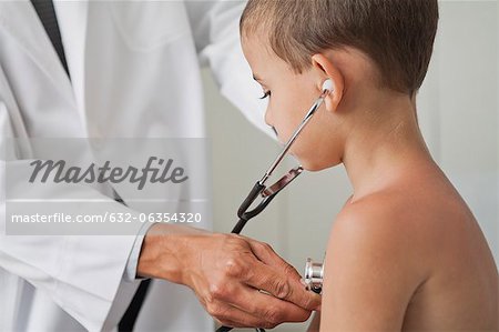 Doctor letting boy listen to own chest with stethoscope