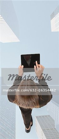 Businesswoman using digital tablet while walking on superimposed image of skyscrapers