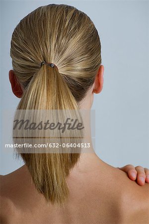 Back view of woman's brown hair tied in a ponytail stock photo