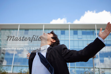 Businessman standing in front of building with arms outstretched
