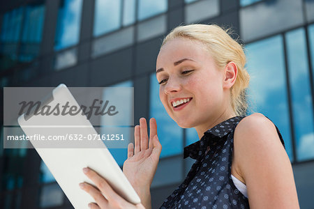 Young woman waving at digital tablet
