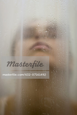 Woman behind wet shower curtain, head back, close-up