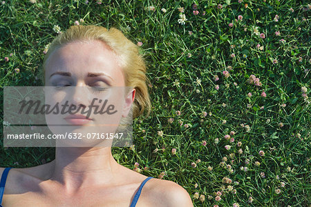 Young woman napping on grass, portrait