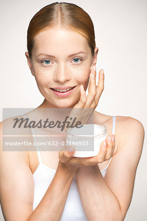 Young woman moisturizing face