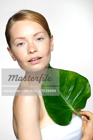 Young woman with tropical plant leaf, portrait