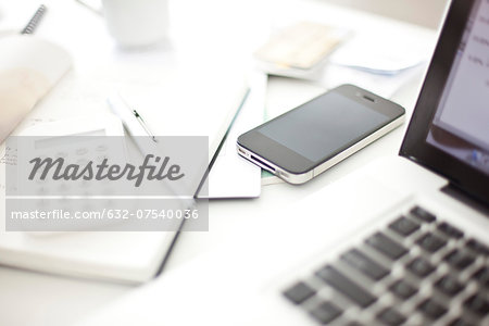 Smartphone resting on desk in in home office Smartphone resting on desk in in home office