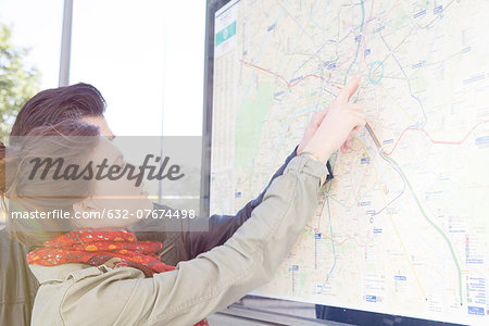 Tourist couple looking at outdoor city map at tourist information station