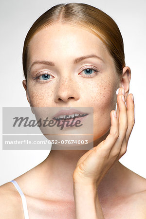 Young woman applying moisturizer to face