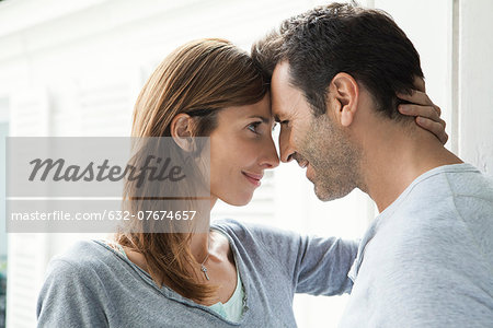 Couple touching noses by window