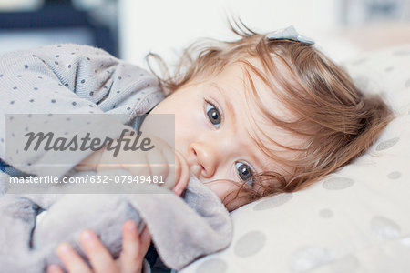 Baby girl lying down, sucking thumb, portrait