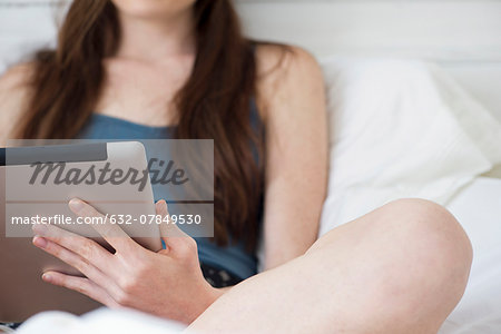 Woman using digital tablet in bed