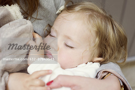 Baby girl sleeping in mother's arms, cropped