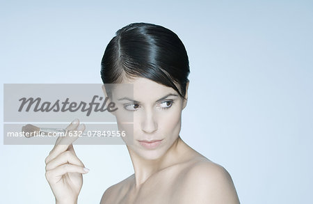 Woman holding make-up brush, looking away