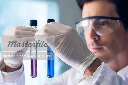Scientist scrutinizing test tubes in lab