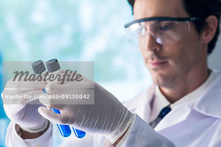 Scientist scrutinizing test tubes containing blue liquid in lab Scientist scrutinizing test tubes containing blue liquid in lab