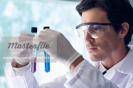 Scientist scrutinizing test tubes in lab Scientist scrutinizing test tubes in lab