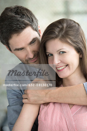 Woman smiling as husband embraces her, portrait