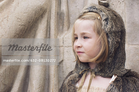 Little girl wearing hooded fur cloak outdoors, portrait