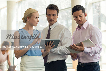 Businesswoman showing colleagues digital tablet