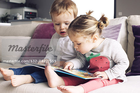 Young siblings looking at book together