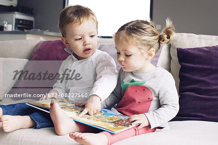 Young siblings looking at book together