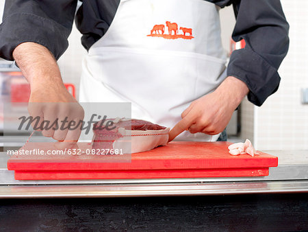 Butcher tying twine around meat cut