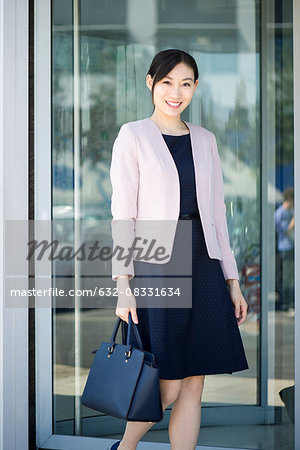 Businesswoman exiting building, smiling cheerfully
