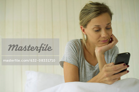 Woman sitting in bed using smartphone