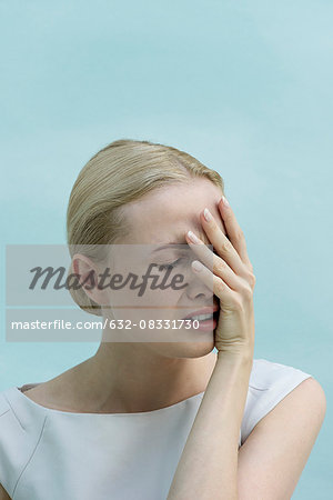 Woman covering face with hand and grimacing