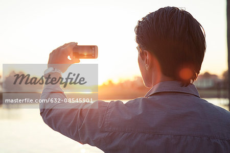 Man photographing sunset with smartphone