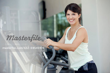 Woman exercising in fitness club, smiling cheerfully
