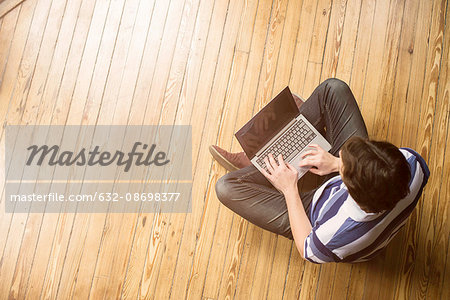 Man sitting indian style on floor using laptop computer