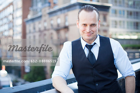 Businessman on balcony, smiling, portrait