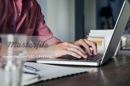 Man typing on laptop computer, cropped