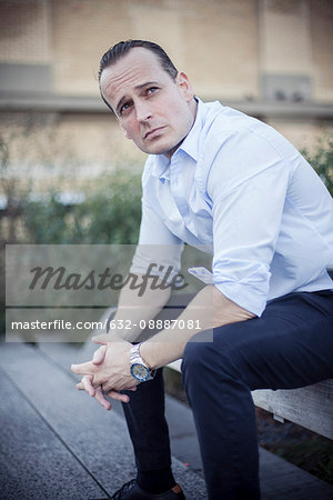 Businessman sitting outdoors with worried expression on face