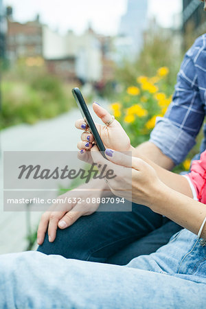 Couple using smartphone outdoors, cropped