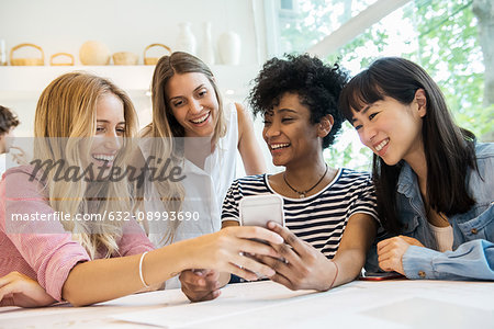 Friends looking at smartphone together in cafe