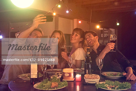 Friends posing for group selfie at dinner party Friends posing for group selfie at dinner party