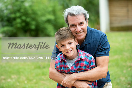 Grandfather embracing grandson outdoors, portrait