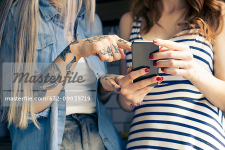 Women using smartphone together, cropped