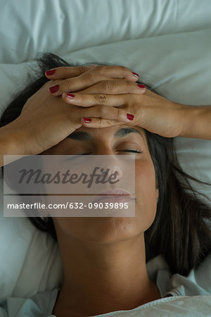 Woman lying in bed with hands on forehead