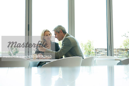 Businesspeople using laptop in cafeteria