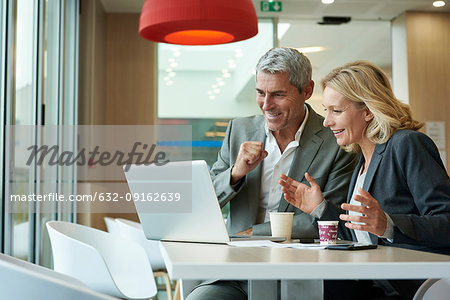 Businesspeople using laptop in cafeteria