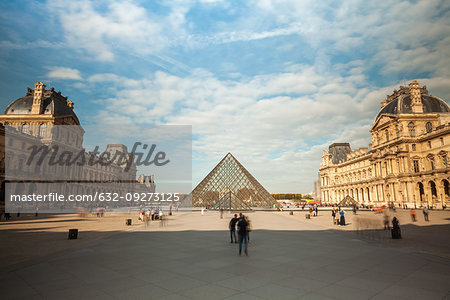 View of the Louvre Museum and the glass pyramid with tourists