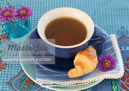Cup of tea, with saucer and croissant
